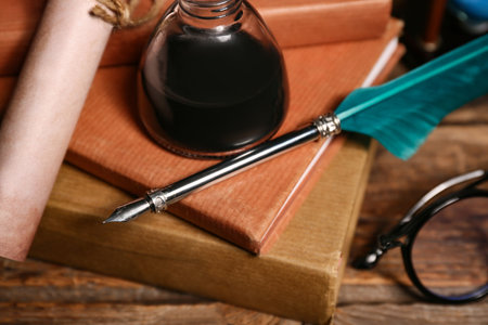 Old books with nib pen, inkwell and scroll on wooden backgroundの写真素材