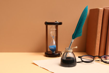 Old paper sheet with books, nib pen, inkwell, glasses and hourglass on color backgroundの写真素材