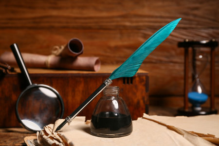 Old book with nib pen and magnifying glass on wooden backgroundの写真素材