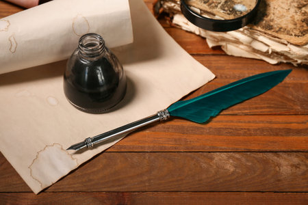 Paper sheet with nib pen and inkwell on wooden background