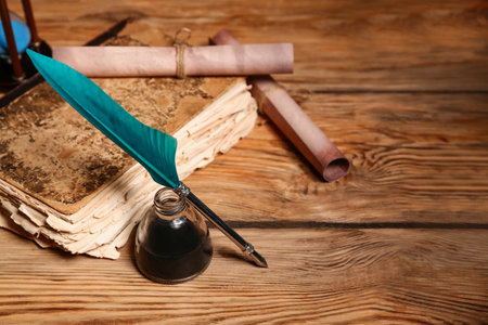 Old book with nib pen, inkwell and scrolls on wooden backgroundの写真素材