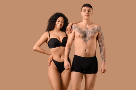 Young couple in stylish underwear on beige backgroundの写真素材
