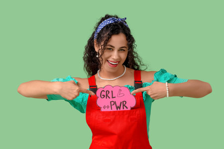 Young African-American pin-up woman pointing at GRL PWR sign on green background. Women's History Monthの写真素材
