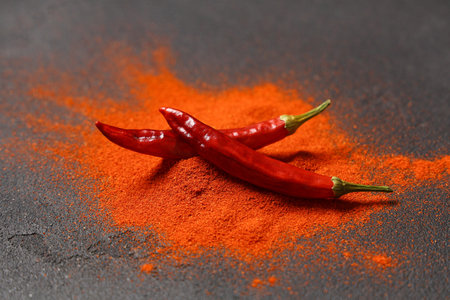 Red chili powder and peppers on black background