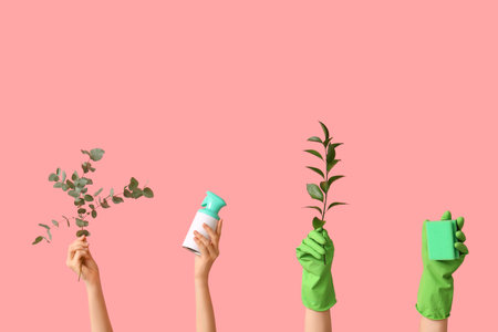 Female hands in rubber gloves with bottle of detergent, sponge and plant branches on pink backgroundの写真素材