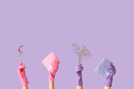 Many female hands in rubber gloves with rags and flowers on purple backgroundの写真素材