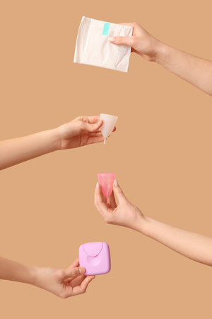 Female hands with menstrual cups, pad and tampons storage box on beige backgroundの写真素材