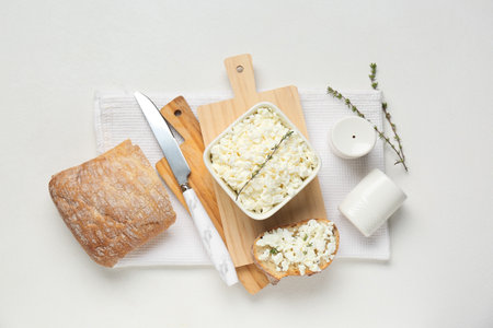 Bowl of fresh cottage cheese with thyme and bread slice on white backgroundの写真素材