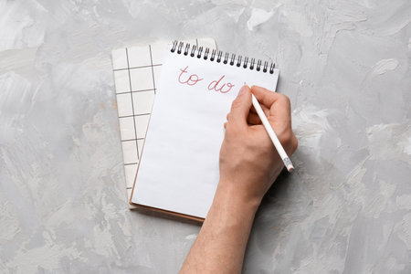 Male hand with to-do list and notebooks on grunge gray backgroundの写真素材