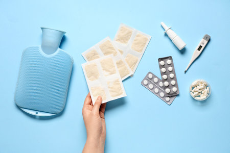 Woman holding mustard plasters and medical supplies on blue backgroundの写真素材