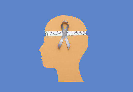 Paper human head with brain and gray awareness ribbon on blue background. Cancer conceptの写真素材