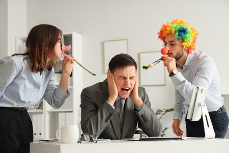 Young colleagues with party whistles in office. April Fools' Day celebrationの写真素材