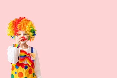 Little girl in clown costume on pink background. April Fools' Day celebrationの写真素材