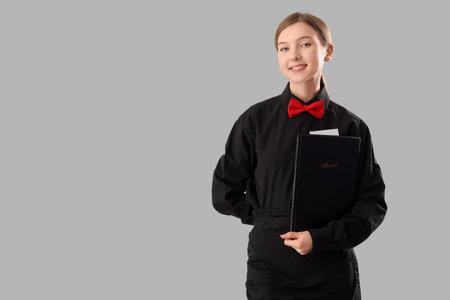Young waitress with menu on light backgroundの写真素材