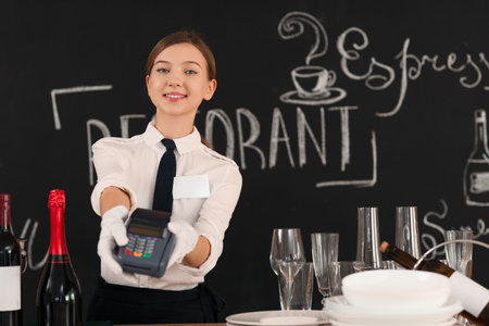Young waitress with payment terminal in restaurantの写真素材