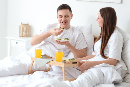 Young couple having breakfast in bedroomの写真素材