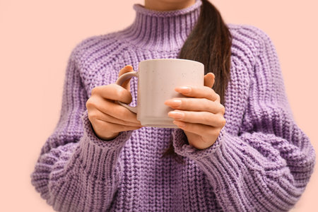 Young woman with cup of hot tea on pink background, closeupの写真素材
