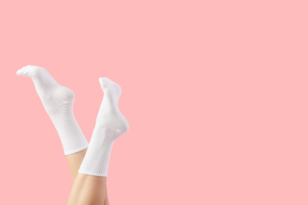 Legs of young woman in stylish white socks on pink background