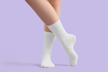 Legs of young woman in stylish white socks on lilac backgroundの写真素材
