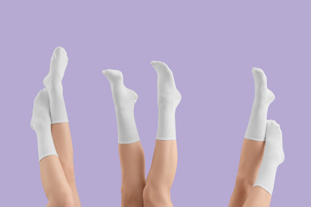 Legs of young women in stylish white socks on lilac backgroundの写真素材