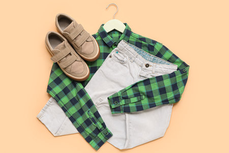 Hanger with stylish children's shirt, jeans and shoes on color backgroundの写真素材