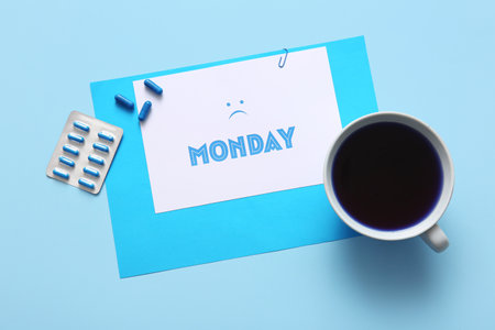 Paper sheet with the word MONDAY, sad face, cup of coffee and pills on blue backgroundの写真素材