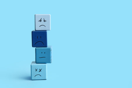 Cubes with drawn sad faces on blue backgroundの写真素材