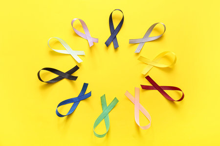 Composition with different ribbons on yellow background. World Cancer Day