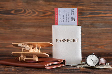 Passport with ticket, toy plane, money and wristwatch on wooden backgroundの写真素材