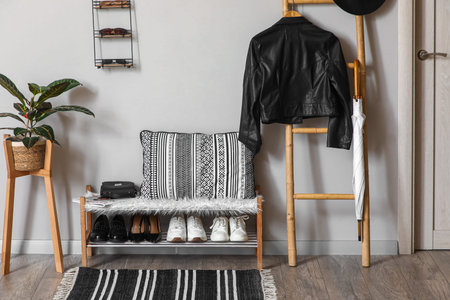 Bench with stand for shoes and jacket hanging on ladder in interior of hallwayの写真素材