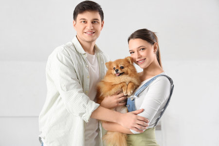 Young couple with Pomeranian dog hugging in their new houseの写真素材