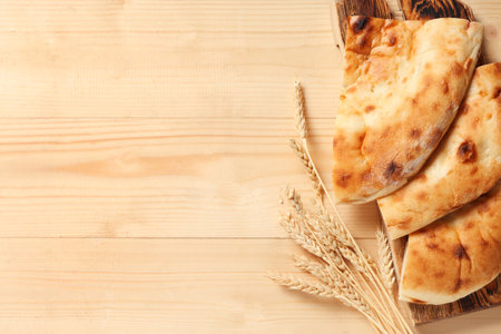 Board with pieces of tasty lavash and wheat spikelets on wooden backgroundの写真素材