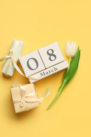 Cube calendar with date 8 MARCH, gift boxes and beautiful tulip on yellow background. Women's Day celebrationの写真素材