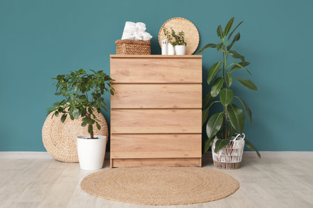 Houseplants and wicker basket with clean folded towels on commode near blue wallの写真素材