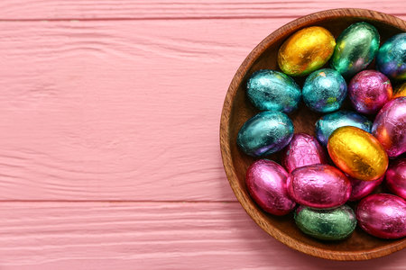 Bowl of chocolate Easter eggs in foil on pink wooden backgroundの写真素材