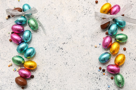 Chocolate Easter eggs in foil with sprinkles and bows on white grunge backgroundの写真素材