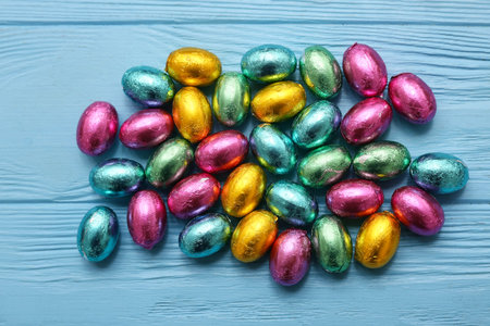 Many chocolate Easter eggs on blue wooden background
