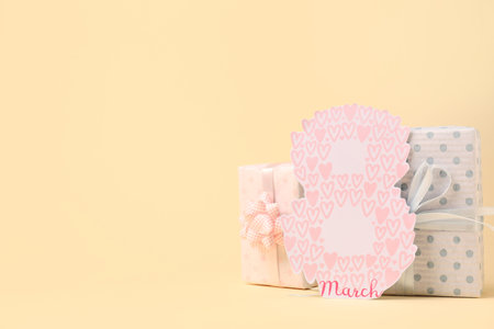 Gift boxes and greeting card for Women's Day celebration on beige background