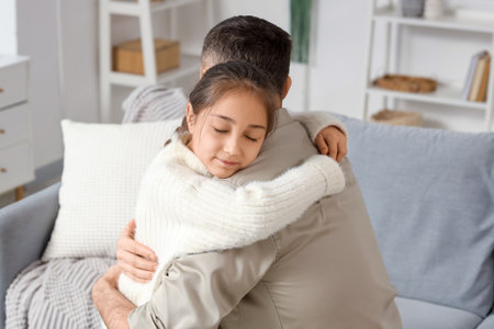Apologetic father hugging his daughter at homeの写真素材