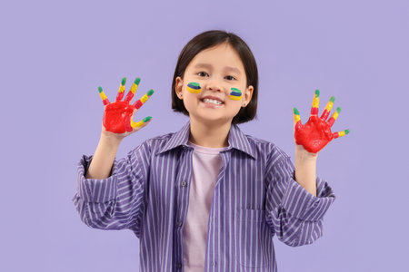 Cute Asian girl in paint on lilac backgroundの写真素材