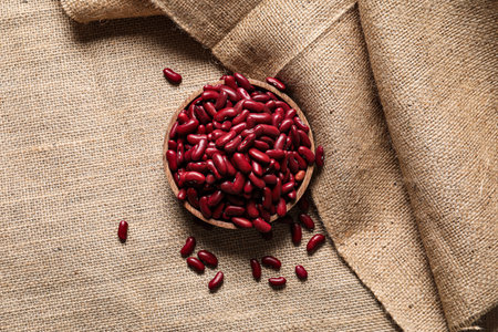 Bowl with raw beans on burlap fabricの写真素材