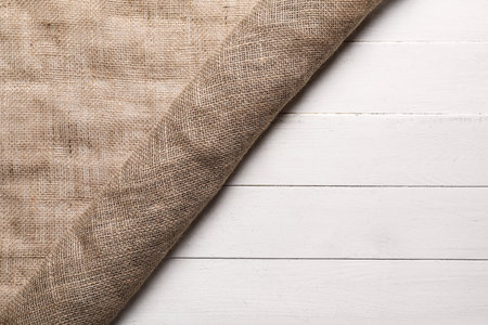 Rolled burlap fabric on light wooden background