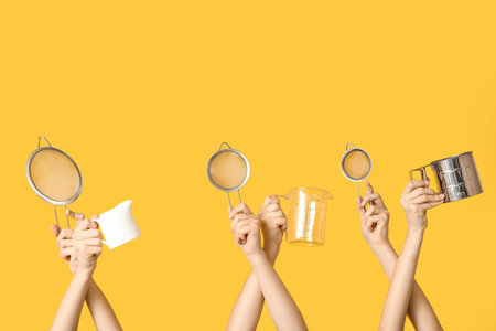 Female hands holding sieves with milk jug and measuring cup on yellow background