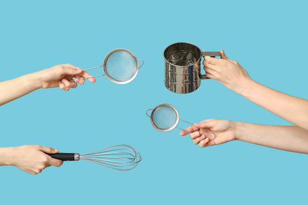 Female hands holding sieves with whiskey on blue backgroundの写真素材