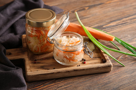 Glass jar with tasty sauerkraut and carrot on wooden background. Closeupの写真素材