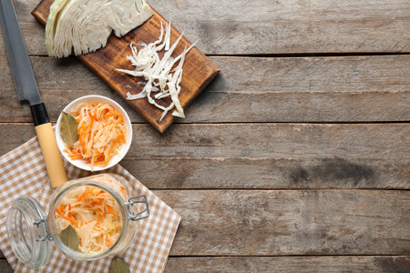 Glass jars and bowl with tasty sauerkraut and cabbage on wooden background. Top viewの写真素材