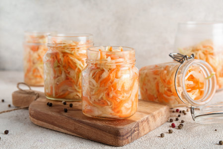Jars of sauerkraut and scattered peppercorns on table against gray background. Closeupの写真素材