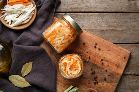 Tasty sauerkraut in jar with ingredients on wooden background. Top viewの写真素材