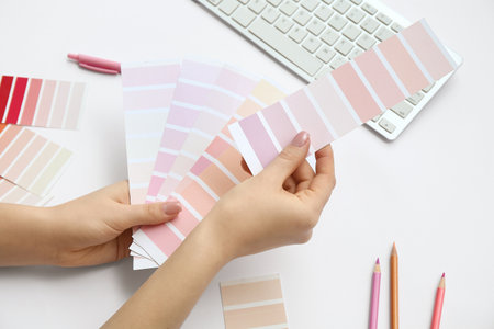 Female hands with paint color palettes, pencils and computer keyboard on light background, closeupの写真素材