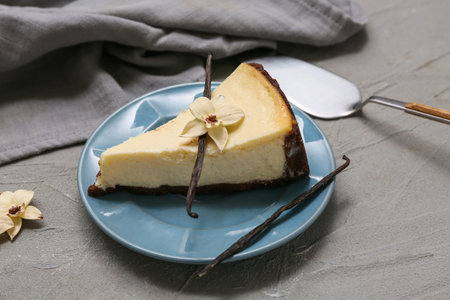 Plate with piece of sweet vanilla cheesecake on gray backgroundの写真素材